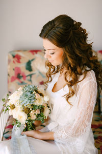 Beautiful woman with flowers sitting at home