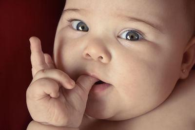 Close-up portrait of cute baby girl sucking finger