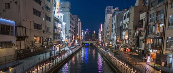 Panoramic view of canal amidst buildings in city at night