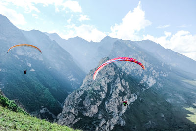 People paragliding on mountain peak against sky