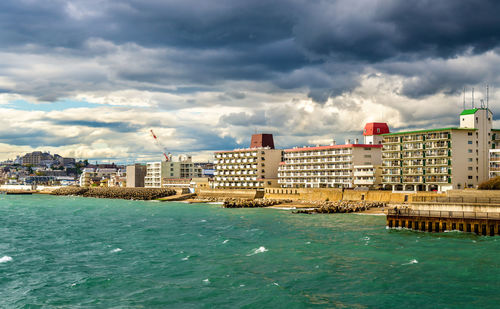 Sea by buildings against sky in city