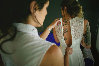 Rear view of woman zipping bride dress