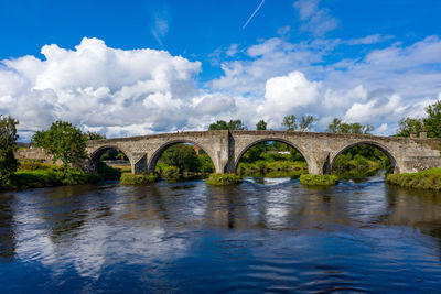 Arch bridge over river against sky