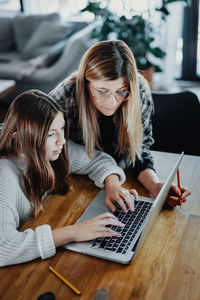 High angle view of mother by daughter using laptop on table