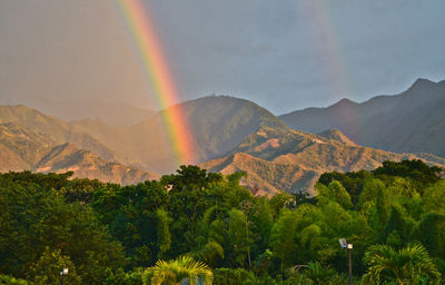 Scenic view of rainbow over mountains against sky