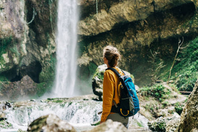 Athletic active hiking woman with a backpack exploring a waterfall in a canyon.