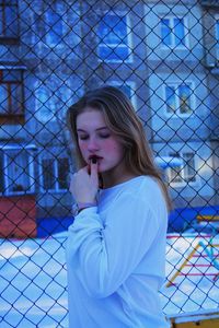 Young woman looking away while standing on fence