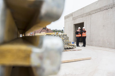 Two men wearing safety vests talking on construction site