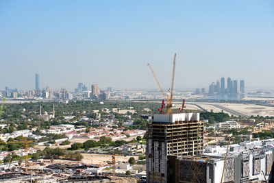 Aerial view of crane and buildings against clear sky