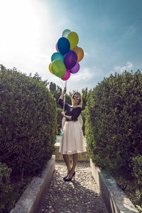 Woman with colorful balloons on walkway against sky