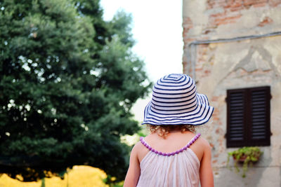 Rear view of girl standing against building