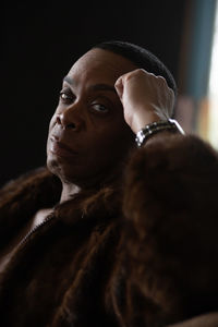 Portrait of man wearing fur coat sitting indoors