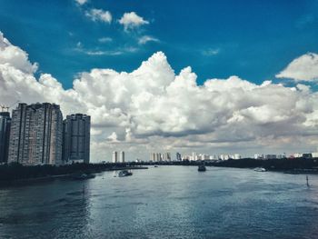 City at waterfront against cloudy sky