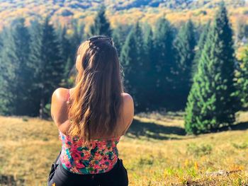 Rear view of woman standing against trees