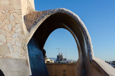 Arch bridge against clear blue sky in city