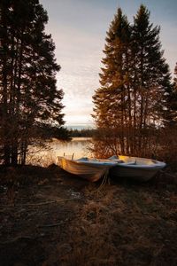 Boats moored on shore by lake against sky