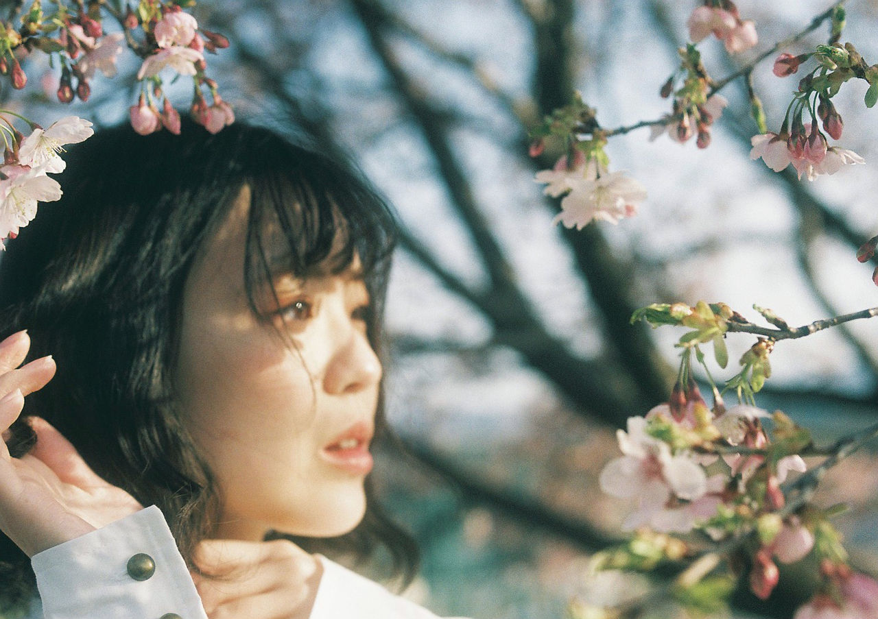 CLOSE-UP PORTRAIT OF BEAUTIFUL WOMAN WITH FLOWERS ON BRANCH