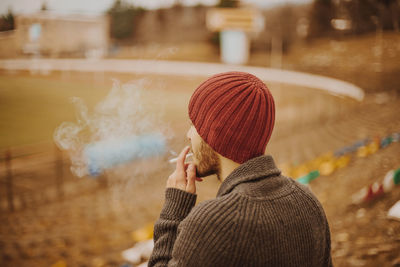 Man wearing warm clothing while smoking cigarette outdoors