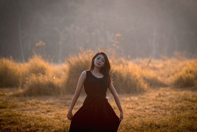 Portrait of woman in dress standing on field