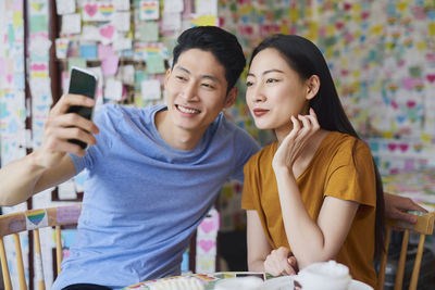 Smiling young woman using mobile phone at table