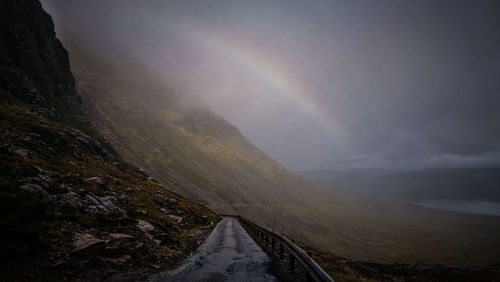 Scenic view of road by mountains against sky