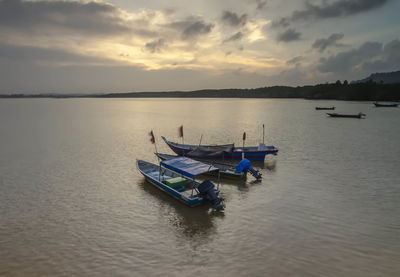 Boat moored in lake against sky during sunset