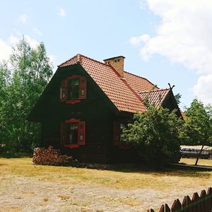 House by tree and building against sky