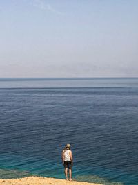 Rear view of man looking at sea against sky