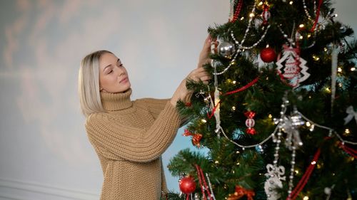 Portrait of young woman standing by christmas tree
