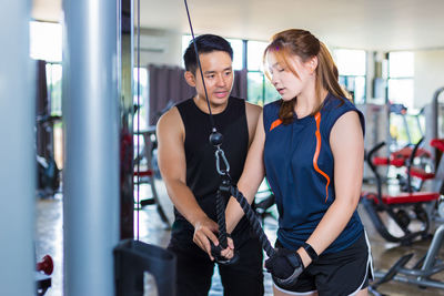 Instructor teaching woman exercising in gym