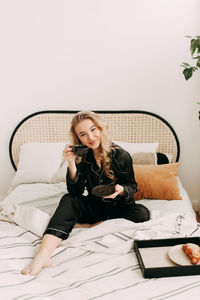 Young woman sitting on bed at home