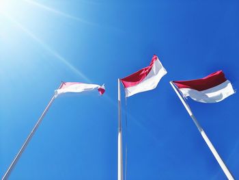 Low angle view of flags against clear blue sky