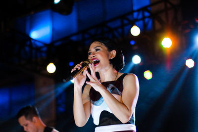 Smiling woman performing on stage at night