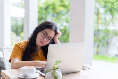 Young woman using mobile phone while sitting on table