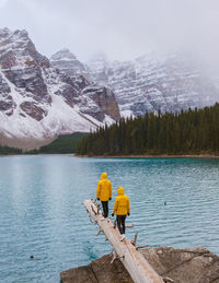 Rear view of man standing by lake