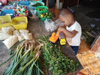 High angle view of cute boy playing with vegetables for sale at market