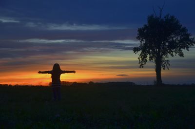 Silhouette person standing on field against sky during sunset