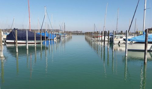 Sailboats moored on sea against clear sky