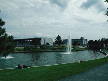 Built structure by river against cloudy sky