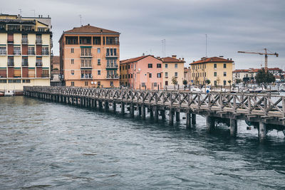 Bridge over river by buildings in city against sky