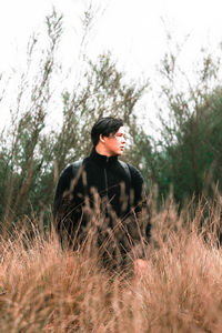 Young man looking away while standing on land