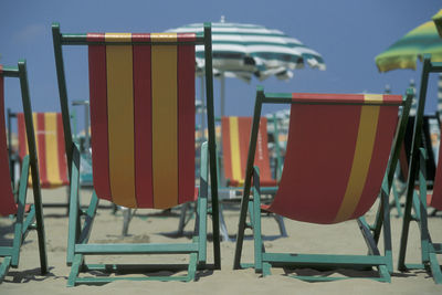 Close-up of empty chairs at beach against sky