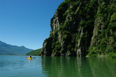 Person kayaking in lake against sky