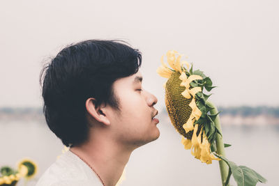 Close-up of man smelling sunflower