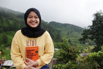 Portrait of smiling woman standing against plants