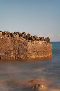 Rocks on sea shore against sky