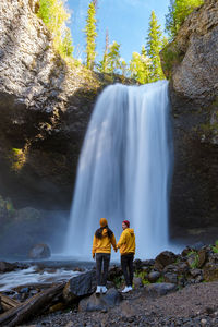 Rear view of man standing against waterfall