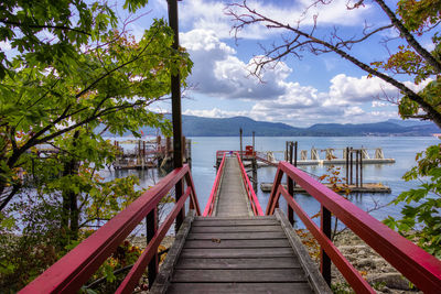 Wooden bridge over lake against sky