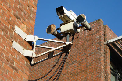 Low angle view of security camera mounted on brick wall