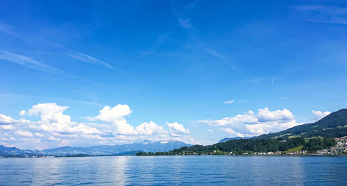 Scenic view of sea and mountains against blue sky